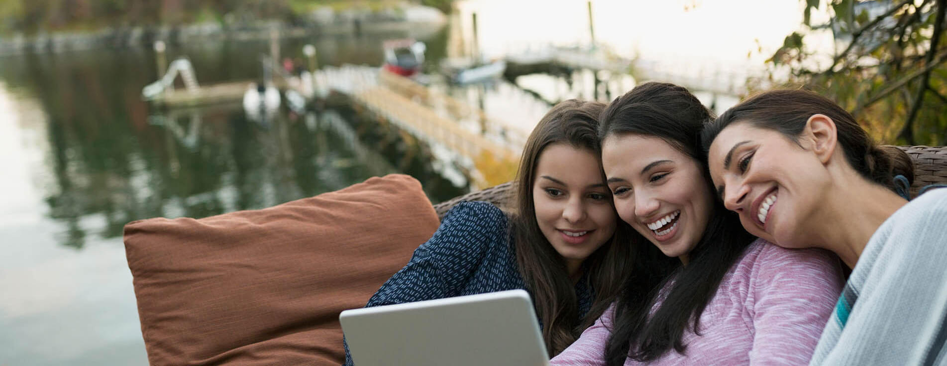 Young women video chatting by a lake.